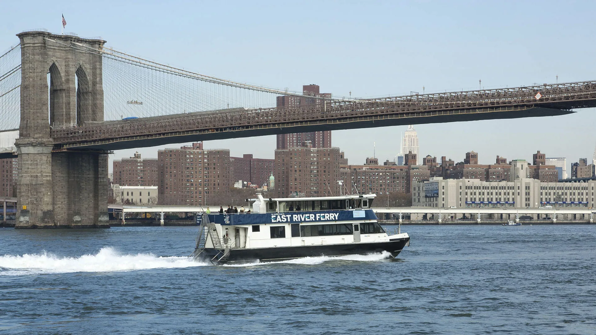 Ferry no East River com a ponte do Brooklyn ao fundo