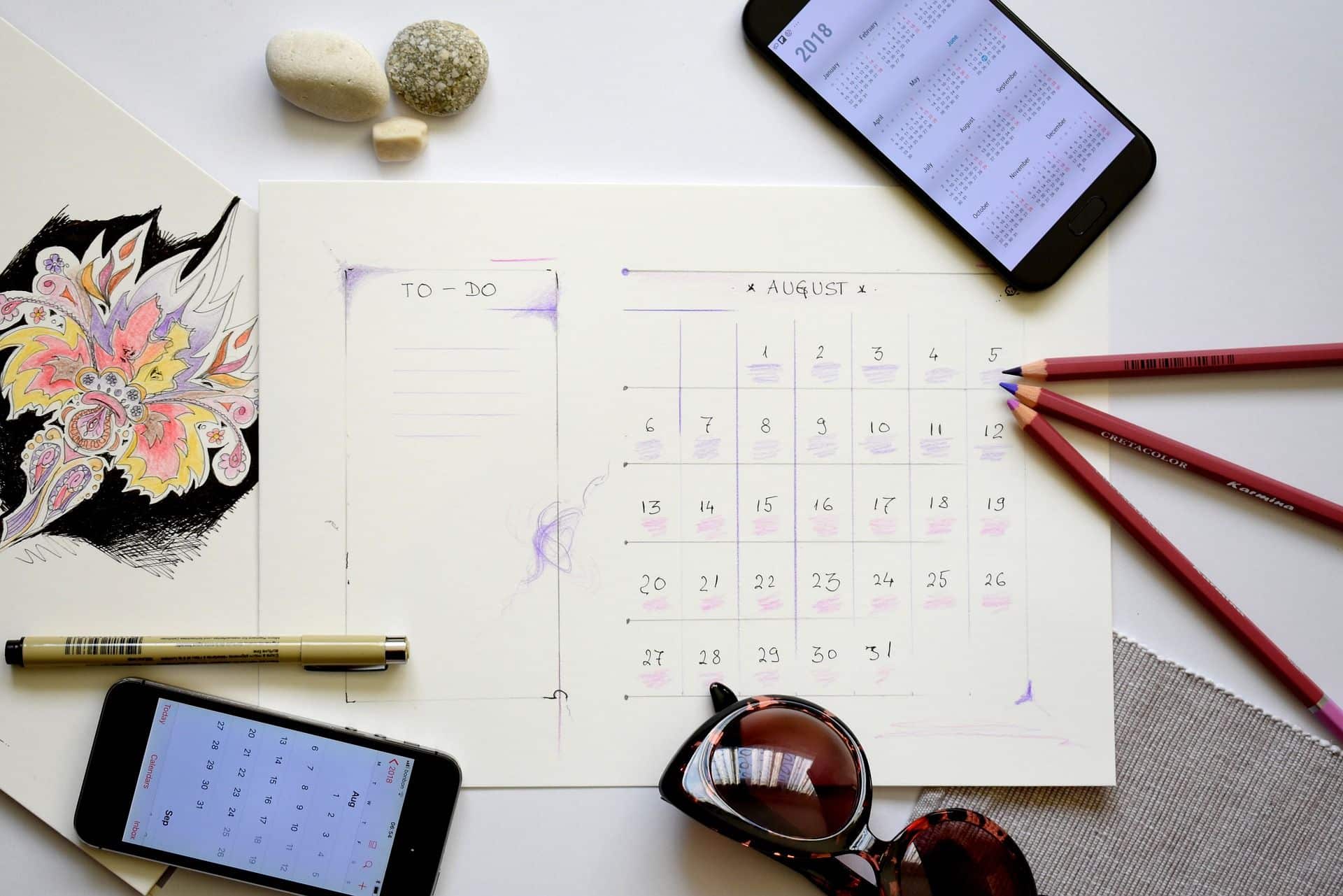 celular, calendário e lápis em cima de mesa
